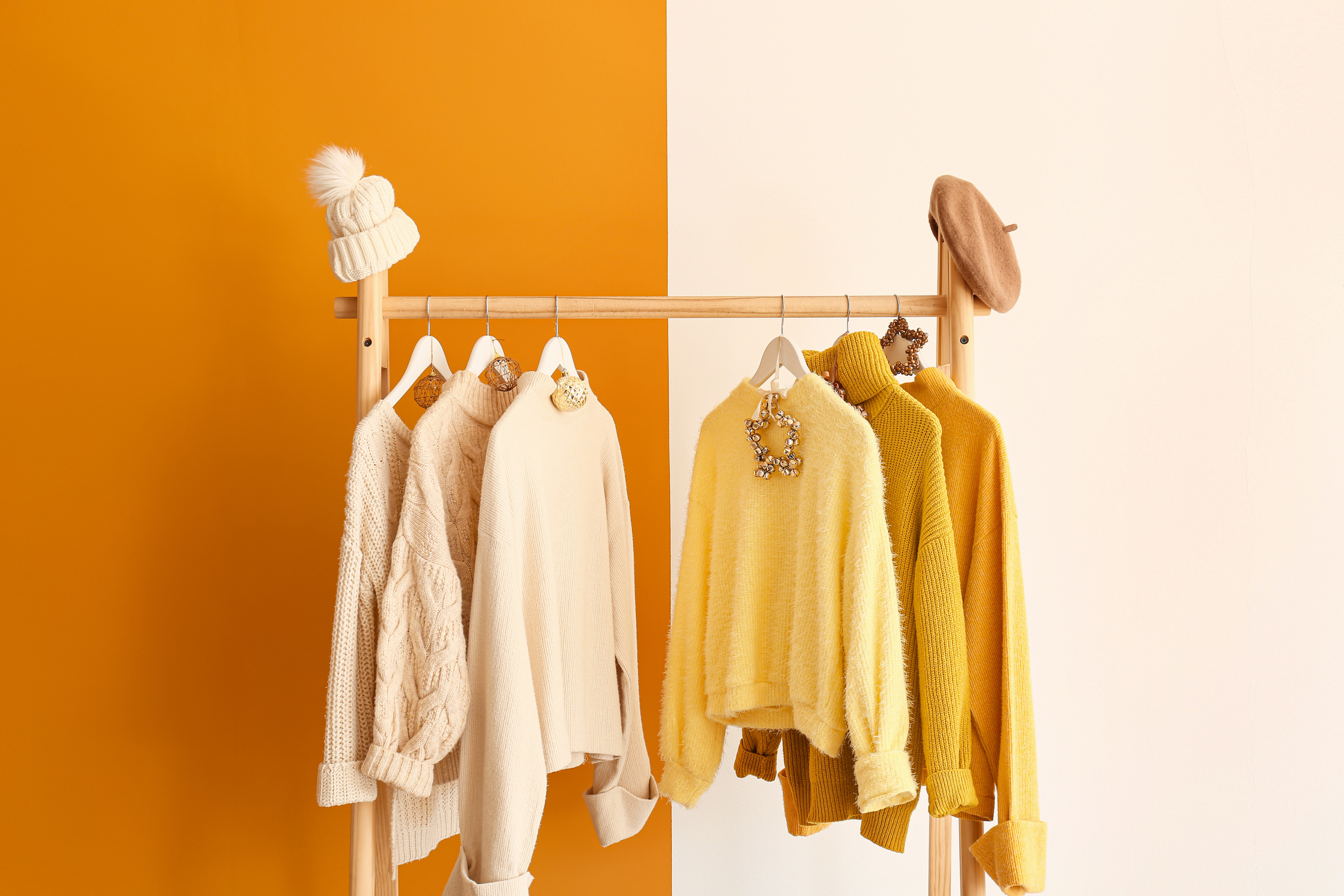 Rack with Winter Clothes on Yellow Background